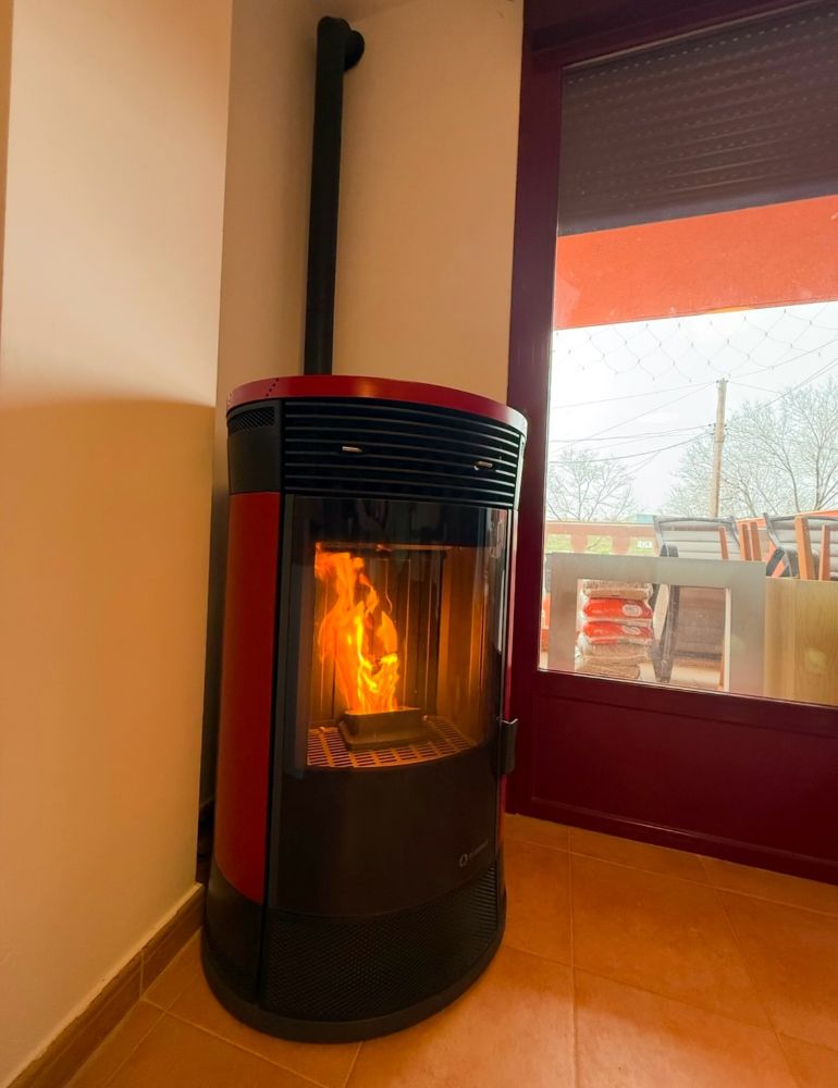 Estufa de pellet roja instalada y encendida en un salón